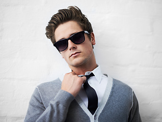 Image showing Face, fashion and sunglasses with cool man in studio on white background for attitude or style. Portrait, shades and tie with confident young person or model in casual or trendy clothes outfit