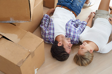 Image showing Couple, boxes and smile on floor for real estate, new home or property investment with romance or love. Moving, man and woman with happy and holding hands for fresh start, achievement and dream house