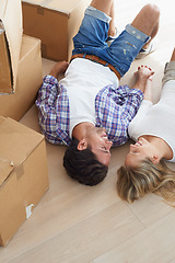 Image showing Couple, boxes and happy on floor for real estate, new home or property investment with romance or love. Moving, man and woman with smile or holding hands for fresh start, achievement and dream house