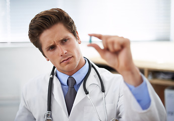 Image showing Curious man, doctor and thinking with pill for healthcare, cure or drugs at hospital or office. Male person, surgeon or medical nurse looking at medication in research, study or examination at clinic