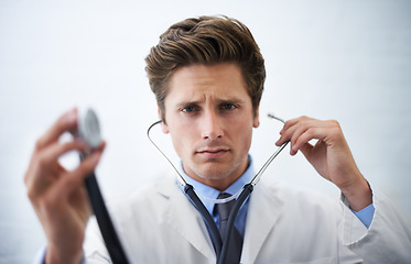 Image showing Stethoscope, serious and portrait of doctor in office for medical consultation at hospital. Doubt, thinking and professional young male healthcare worker with equipment for career at medicare clinic