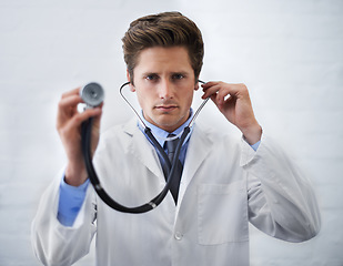 Image showing Serious, portrait and man doctor with stethoscope in his office for medical consultation at hospital. Listen, career and professional young male healthcare worker or intern at medicare clinic.