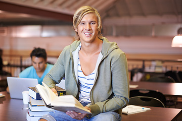 Image showing Reading book, portrait or student in library at university, college or school campus for education. Knowledge, smile or happy man with scholarship studying research or learning information at table