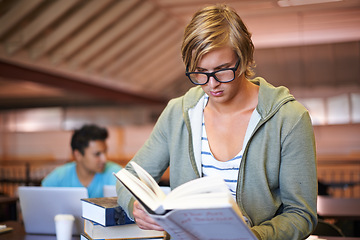 Image showing Reading book, knowledge or student in library at university, college or school campus for education. Glasses, nerd or male person serious about scholarship studying, research or learning information