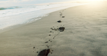 Image showing Footprints in sand, beach and ocean with sunrise, light and environment, travel and closeup with tropical landscape. Sun, nature and sea, waves and destination for vacation, outdoor and mockup space