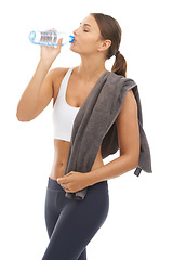 Image showing Woman, towel and drinking water in studio for exercise recovery, energy and healthy detox on white background. Thirsty model, fitness and bottle for sports nutrition, weight loss diet and hydration