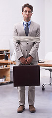 Image showing Sad businessman in office tied up in rope with depression, control and prisoner in law firm. Serious attorney, lawyer or legal consultant bound at work, corporate hostage with briefcase and stress.