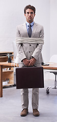 Image showing Scared businessman in office tied up in rope with depression, control and prisoner in law firm. Serious attorney, lawyer or legal consultant bound at work, corporate hostage with briefcase and fear