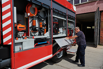 Image showing A dedicated firefighter preparing a modern firetruck for deployment to hazardous fire-stricken areas, demonstrating readiness and commitment to emergency response