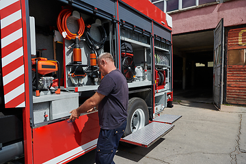 Image showing A dedicated firefighter preparing a modern firetruck for deployment to hazardous fire-stricken areas, demonstrating readiness and commitment to emergency response