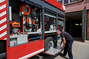 Image showing A dedicated firefighter preparing a modern firetruck for deployment to hazardous fire-stricken areas, demonstrating readiness and commitment to emergency response