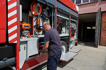 Image showing A dedicated firefighter preparing a modern firetruck for deployment to hazardous fire-stricken areas, demonstrating readiness and commitment to emergency response