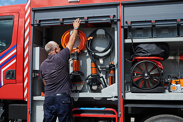 Image showing A dedicated firefighter preparing a modern firetruck for deployment to hazardous fire-stricken areas, demonstrating readiness and commitment to emergency response