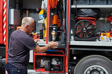 Image showing A dedicated firefighter preparing a modern firetruck for deployment to hazardous fire-stricken areas, demonstrating readiness and commitment to emergency response