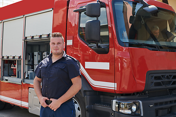 Image showing A confident firefighter strikes a pose in front of a modern firetruck, exuding pride, strength, and preparedness for emergency response