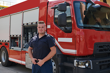 Image showing A confident firefighter strikes a pose in front of a modern firetruck, exuding pride, strength, and preparedness for emergency response