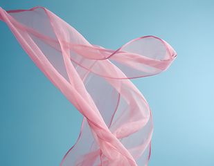 Image showing Flying pink fabric wave on blue sky background and illuminated b