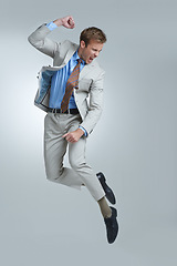 Image showing Businessman, celebration and jumping for success in studio, winner and fist pump for triumph. Male person, professional and victory or accomplishment, cheering and energy or bonus by gray background