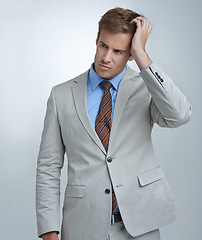 Image showing Confused, thinking and young businessman in a studio with doubt, unsure or decision facial expression. Choice, uncertain and professional male person in a suit with question face by gray background.