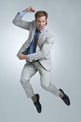 Image showing Businessman, celebration and jumping for achievement in portrait, studio and fist pump for triumph. Male person, professional and victory or success, cheering and energy or win by gray background