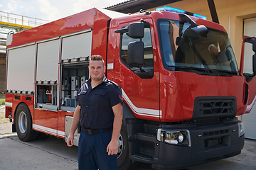 Image showing A confident firefighter strikes a pose in front of a modern firetruck, exuding pride, strength, and preparedness for emergency response