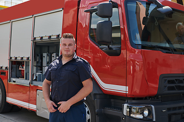 Image showing A confident firefighter strikes a pose in front of a modern firetruck, exuding pride, strength, and preparedness for emergency response