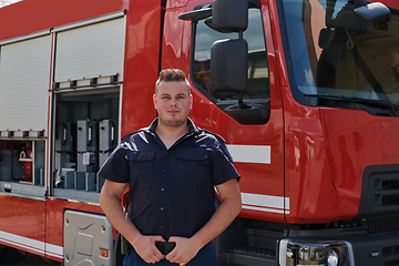 Image showing A confident firefighter strikes a pose in front of a modern firetruck, exuding pride, strength, and preparedness for emergency response