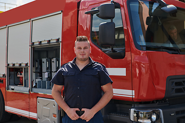 Image showing A confident firefighter strikes a pose in front of a modern firetruck, exuding pride, strength, and preparedness for emergency response