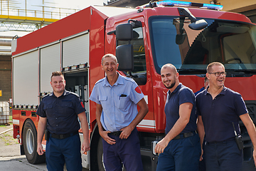 Image showing A skilled and dedicated professional firefighting team proudly poses in front of their state of the art firetruck, showcasing their modern equipment and commitment to ensuring public safety.