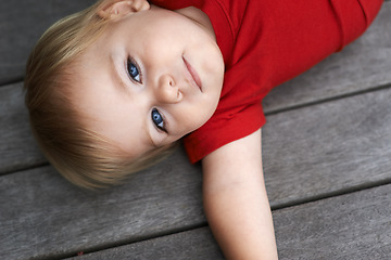 Image showing Baby, playing on floor outdoor for development with portrait, curiosity or early childhood in backyard of home. Toddler, child and relax on ground for wellness, milestone and exploring or aerial view