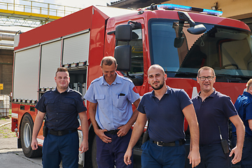 Image showing A skilled and dedicated professional firefighting team proudly poses in front of their state of the art firetruck, showcasing their modern equipment and commitment to ensuring public safety.