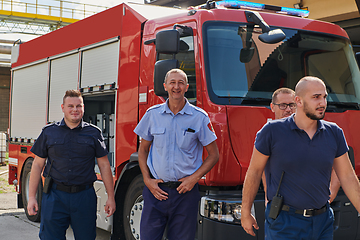 Image showing A skilled and dedicated professional firefighting team proudly poses in front of their state of the art firetruck, showcasing their modern equipment and commitment to ensuring public safety.