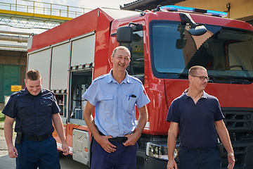 Image showing A skilled and dedicated professional firefighting team proudly poses in front of their state of the art firetruck, showcasing their modern equipment and commitment to ensuring public safety.