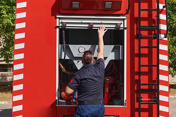 Image showing A dedicated firefighter preparing a modern firetruck for deployment to hazardous fire-stricken areas, demonstrating readiness and commitment to emergency response