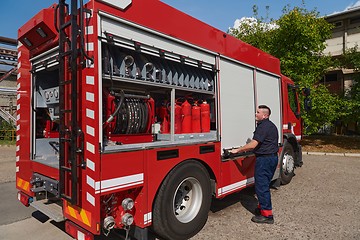 Image showing A dedicated firefighter preparing a modern firetruck for deployment to hazardous fire-stricken areas, demonstrating readiness and commitment to emergency response