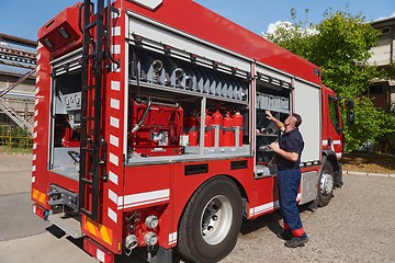 Image showing A dedicated firefighter preparing a modern firetruck for deployment to hazardous fire-stricken areas, demonstrating readiness and commitment to emergency response