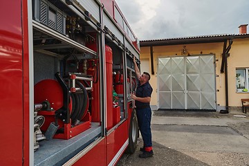 Image showing A dedicated firefighter preparing a modern firetruck for deployment to hazardous fire-stricken areas, demonstrating readiness and commitment to emergency response