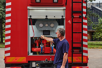 Image showing A dedicated firefighter preparing a modern firetruck for deployment to hazardous fire-stricken areas, demonstrating readiness and commitment to emergency response