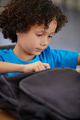 Image showing Boy, education and school bag in a classroom, student and searching with learning, study and table. Kid, child development and happy with a backpack, desk and confident with information and relax