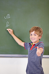 Image showing Portrait, child writing or thumbs up on chalkboard in classroom of elementary school. Boy, education student or happy kid with smile or hand gesture for like emoji, agreement or learning to write