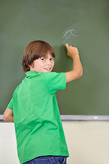 Image showing Portrait, smile and boy drawing on a chalkboard for child development, answers and art for learning. Academic, creative and kid student writing letters in the classroom with art, excited and happy