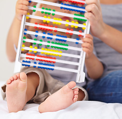 Image showing Abacus, math and baby with mother playing, learning and teaching for child development on bed. Bonding, toy and closeup of mom teaching kid, infant or toddler with counting in bedroom at home.