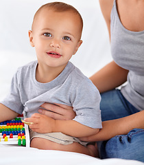 Image showing Abacus, smile and portrait of baby with mother playing, learning and teaching for child development on bed. Bonding, toy and mom with kid, infant or toddler with counting in bedroom at home.
