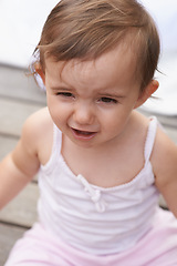 Image showing Sad baby, face and sitting outside of curious toddler, little girl or disappointed on outdoor porch. Closeup of young unhappy child, upset kid or adorable cute newborn with frowning facial expression