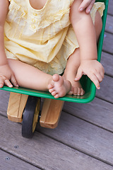 Image showing Baby, child and riding toy wagon in outdoors, plastic and fun activity for childhood. Kid, toddler and wheelbarrow for playing games on porch or deck, closeup and relaxing in construction equipment