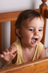 Image showing Baby, laughing and crib at home in bedroom with youth, excited and talking with development. Kid, toddler and nursery in a house with smile, happy and curious with morning with sweet and cute girl