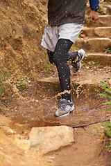 Image showing Puddle, trail or legs of runner running in nature training, cardio exercise or endurance workout for wellness. Steps, splash or closeup of sports athlete on jog in a mountain outdoors for fitness