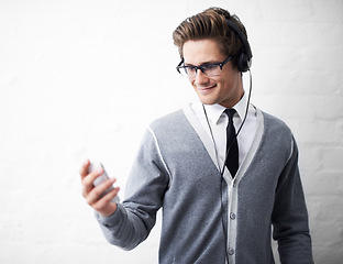 Image showing Man, headphones and listening to audio and relaxing to music by wall background, sound and peace. Male person, smartphone and streaming radio or podcast, playlist and hearing song and mobile app