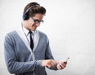 Image showing Man, headphones and listening to audio and phone for music by wall background, sound and peace. Male person, smartphone and streaming radio or podcast, online and hearing song and mobile application