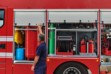 Image showing A dedicated firefighter preparing a modern firetruck for deployment to hazardous fire-stricken areas, demonstrating readiness and commitment to emergency response